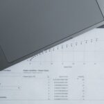 Documentos com dados financeiros ao lado de um notebook