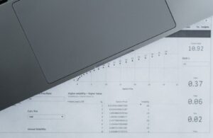 Documentos com dados financeiros ao lado de um notebook
