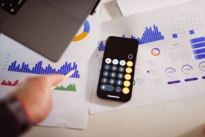 Mesa de trabalho com notebook, gráficos financeiros e calculadora, representando BPO Financeiro e inteligência artificial